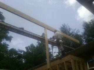 Carpenter setting a ridge beam over a new addition frame — Ice Dam Removal by Roofing Brothers in Montebello