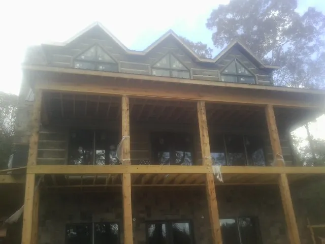 Dormers and porch framing on a large log home under construction — Roof Coating work by our crew in Montebello