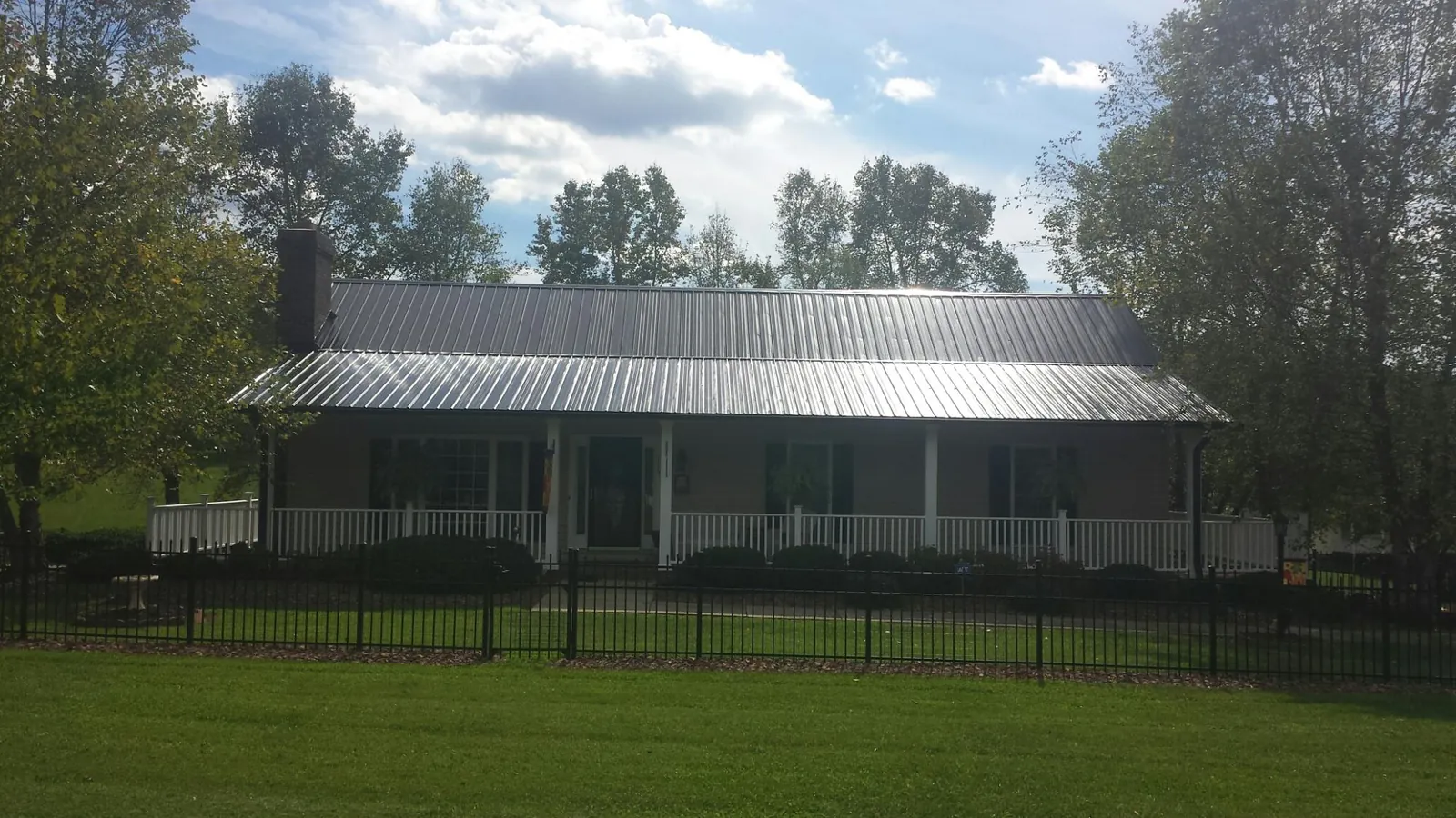 Gray metal roof on a brick ranch with a full width front porch — Gutter Guard Installation work by our crew in Montebello