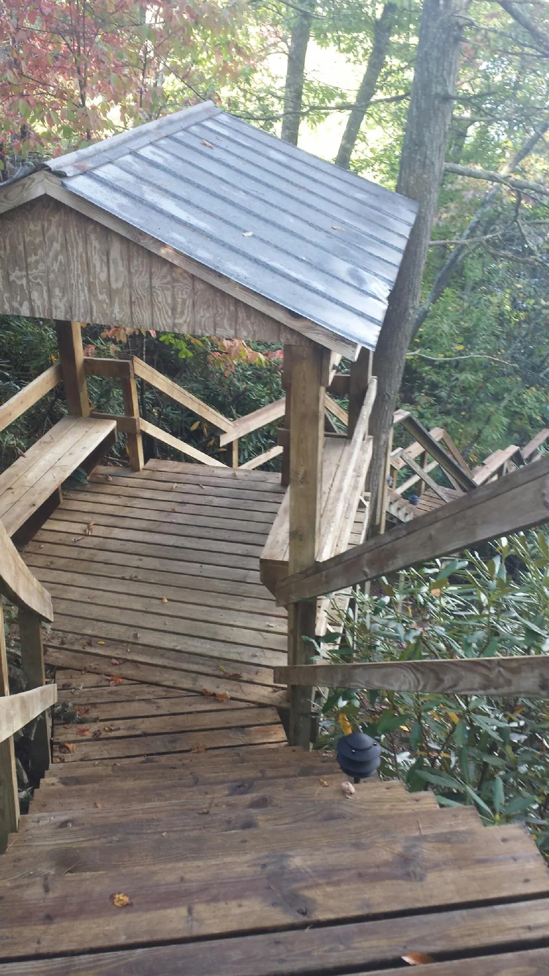 Metal roofed shelter over wooden steps on a wooded walkway — Skylight Repair & Installation work by our crew in Montebello