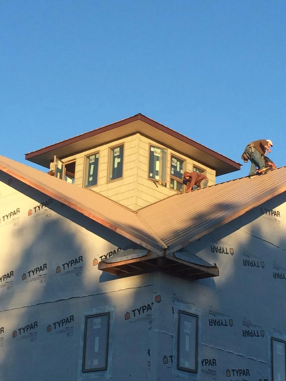 Roofers working around a rooftop cupola on a new metal roof at sunset — Roof Waterproofing in Montebello by Roofing Brothers